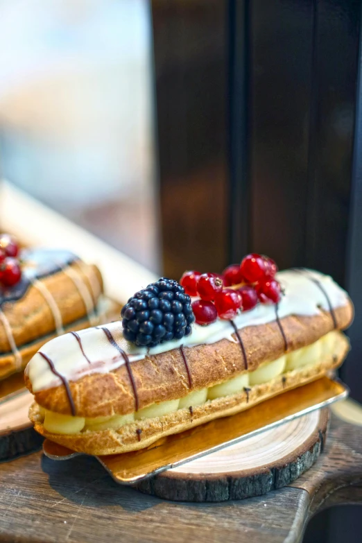 a couple of pastries sitting on top of a wooden cutting board, inspired by Barthélemy Menn, fruit, with a long, napoleonic, long