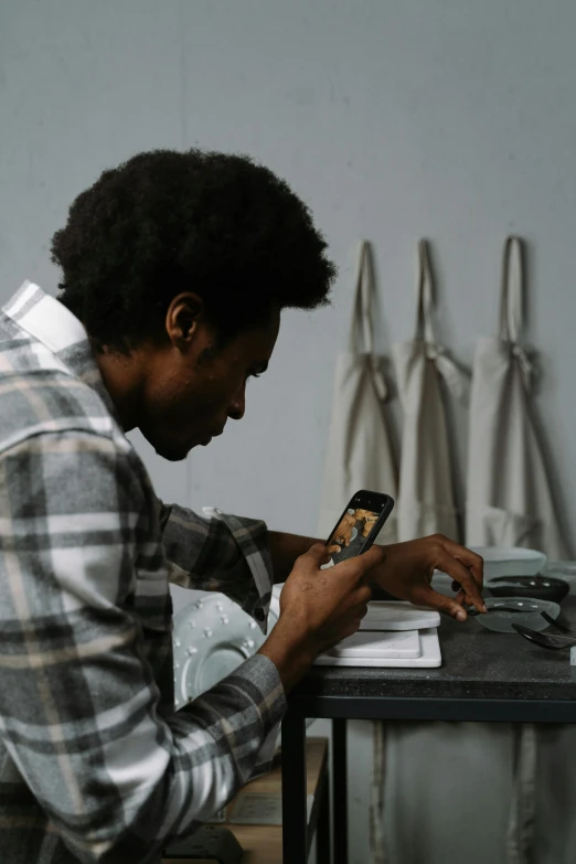 a man sitting at a table using a cell phone, by artist, pexels contest winner, black man with afro hair, inspect in inventory image, maintenance photo, casually dressed