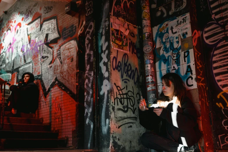 a woman sitting in front of a wall covered in graffiti, pexels contest winner, wall torches, having a snack, avatar image, underground scene