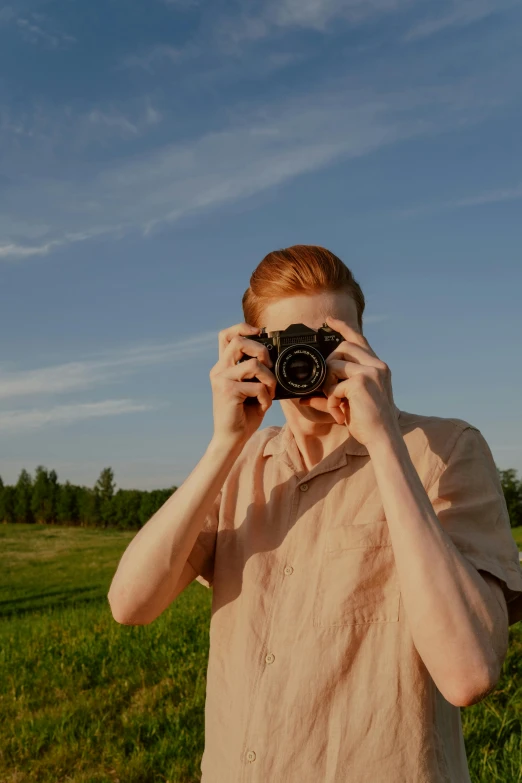 a man taking a picture with a camera in a field, by Julia Pishtar, visual art, red haired teen boy, style of joel meyerowitz, medium format, anton fadeev 8 k