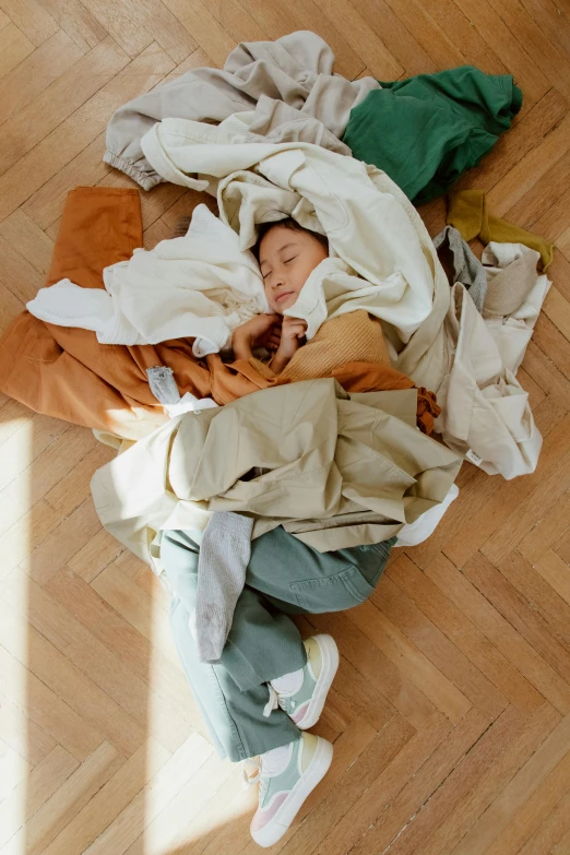 a woman laying on top of a pile of clothes, earthy colors, julia hetta, young child, sleep