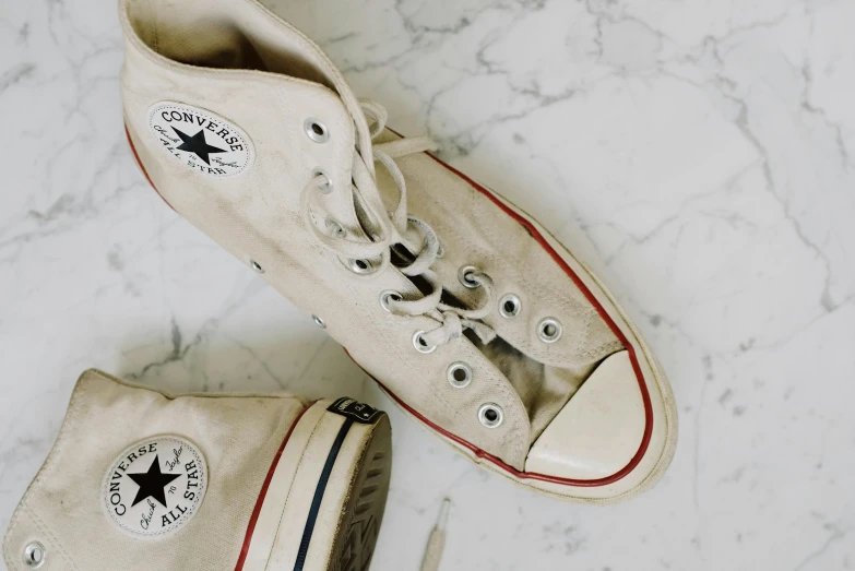 a pair of shoes sitting on top of a marble floor, converse, cream and white color scheme, looking old, on a canva