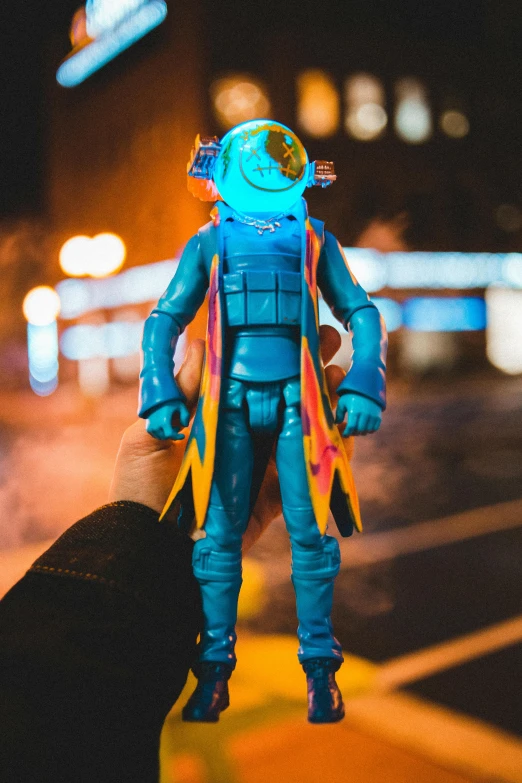 a close up of a person holding a toy, a hologram, unsplash, vinyl action figure, nighttime foreground, full body hero, blue head