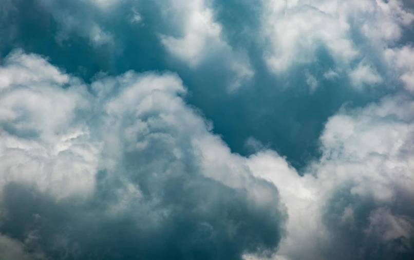 a plane flying through a cloudy blue sky, unsplash, baroque, dark mammatus cloud, teal sky, ignant, loots of clouds