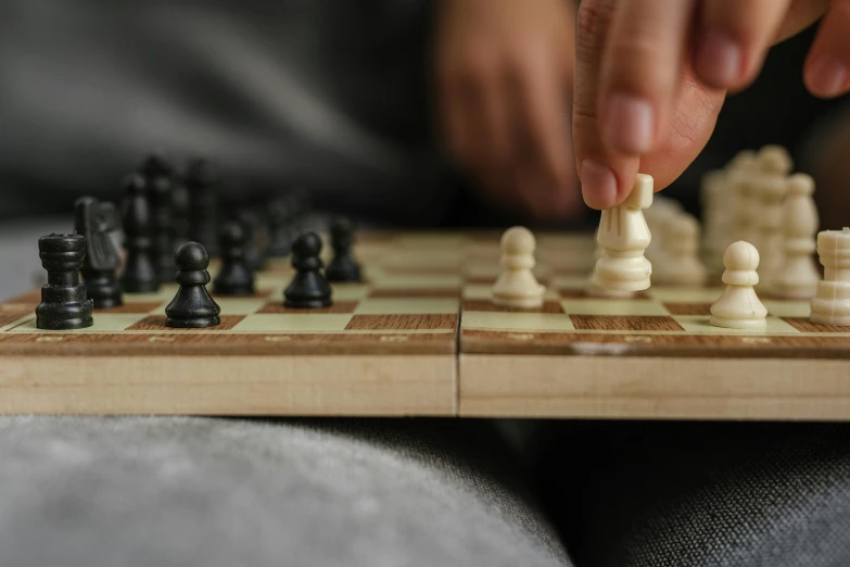 a close up of a person playing a game of chess, zoomed out, worn, from reading to playing games, thumbnail