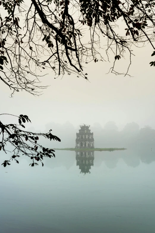 a large body of water surrounded by trees, inspired by Pierre Pellegrini, vietnamese temple scene, hazy fog, flooded ancient tower, unsplash photo contest winner