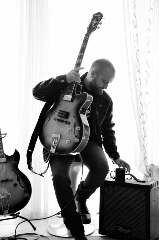 a black and white photo of a man with a guitar, by Dave Melvin, happening, adam varga, kneeling, leaving a room, profile picture