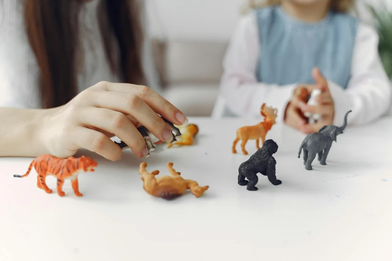 a little girl playing with toy animals on a table, trending on pexels, resin, 🦩🪐🐞👩🏻🦳, with fingers, environmental