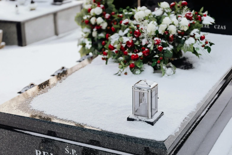 a small silver clock sitting on top of a snow covered grave, casket, silver white red details, evenly lit, subtle detailing