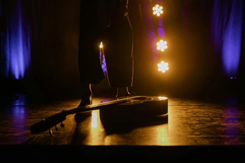 a man standing on top of a stage holding a guitar, pexels contest winner, figuration libre, candlelight, ( ( theatrical ) ), standing sideways, production photo