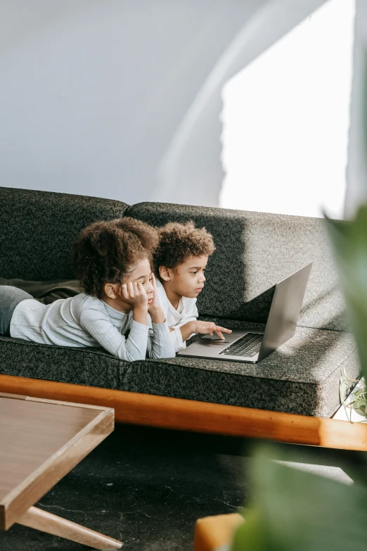 a couple of kids laying on a couch with a laptop, pexels contest winner, afro tech, thumbnail, kids playing, looking away