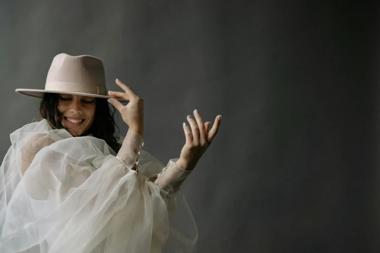 a woman wearing a white dress and a hat, an album cover, inspired by Pietro Longhi, pexels contest winner, waving and smiling, studio shoot, grey mist, taken with canon 5d mk4