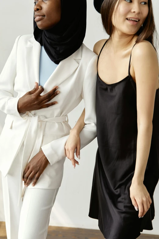 a couple of women standing next to each other, by Nina Hamnett, trending on unsplash, renaissance, white suit and black tie, soft silk dress, muslim, wearing black camisole outfit