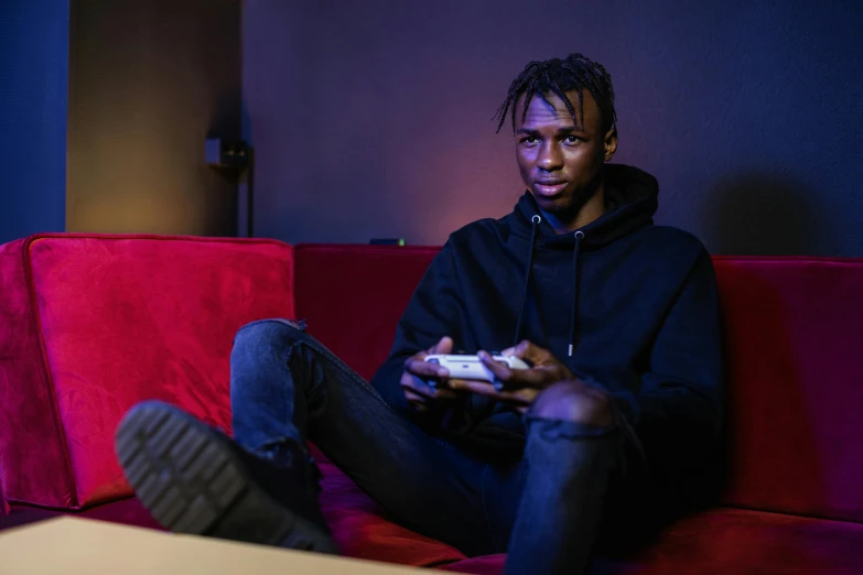 a man sitting on a couch playing a video game, inspired by Gerard Sekoto, pexels contest winner, realism, playboi carti portrait, thin young male, ( ( dark skin ) ), overcast mood