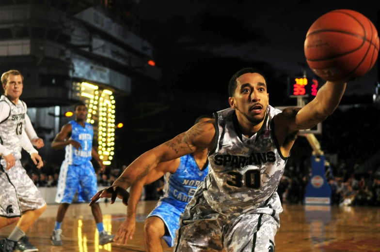 a group of men playing a game of basketball, against a deep black background, square, in 2 0 1 2, university