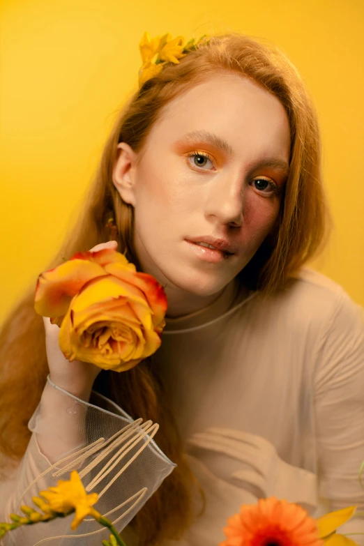 a woman holding a bouquet of flowers in front of her face, an album cover, inspired by Maud Naftel, trending on pexels, yellow and ornage color scheme, hr ginger, holding a rose, studio portrait