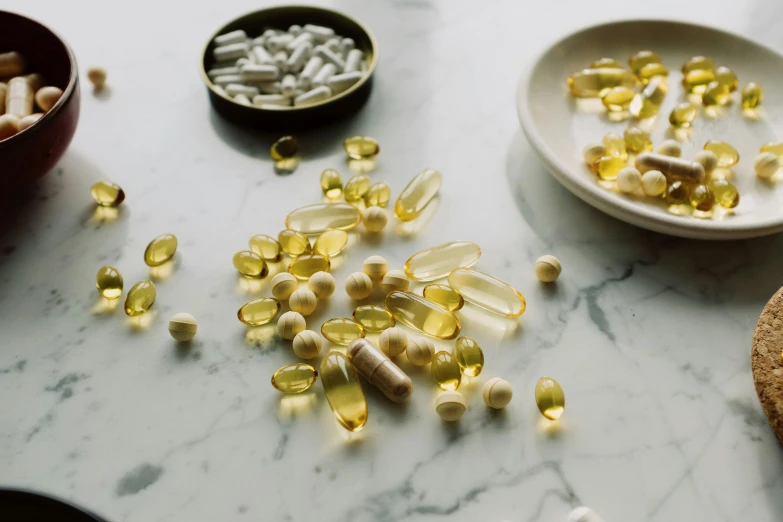 a table topped with lots of different types of pills, by Emma Andijewska, trending on pexels, renaissance, bolts of bright yellow fish, on a white table, “ iron bark, skincare