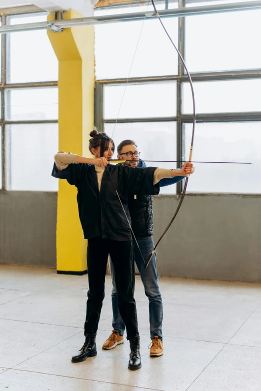 a couple of men standing next to each other with a bow, by Marina Abramović, pexels contest winner, renaissance, in a workshop, sport, katniss everdeen, instagram story