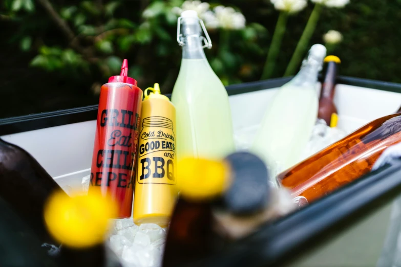 a cooler filled with bottles of beer and condiments, by Julia Pishtar, barbecue, yellow, low detail, feature