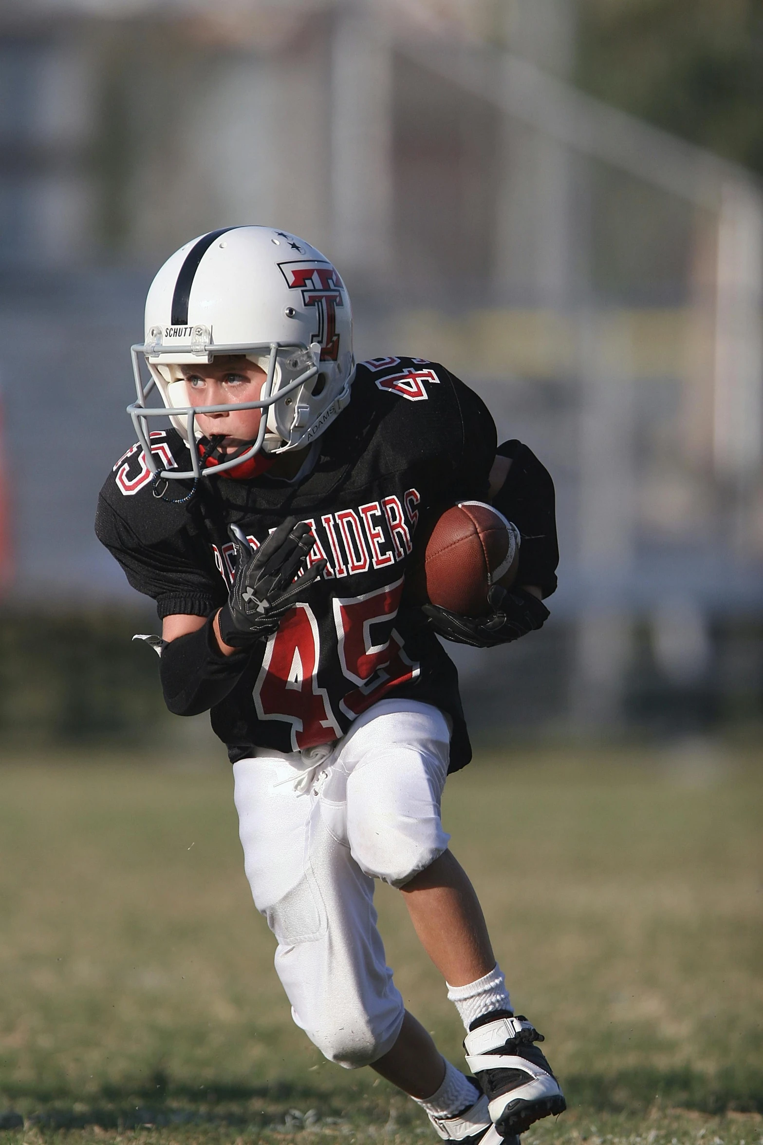 a young boy running with a football on a field, by Daren Bader, happening, full helmet, tournament, profile pic, taken in the late 2010s