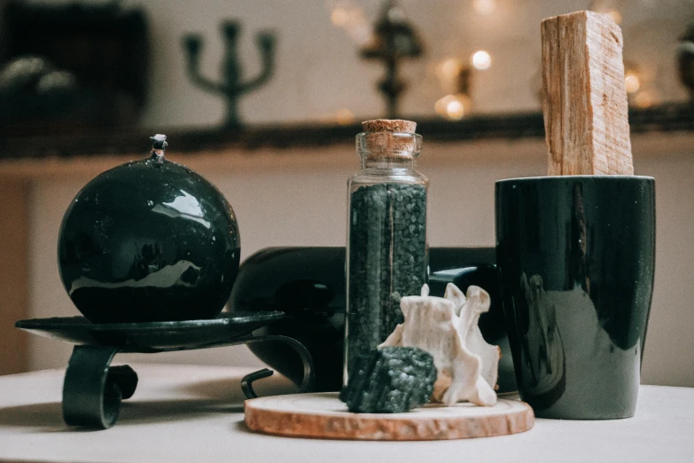 a couple of black vases sitting on top of a table, by Julia Pishtar, trending on pexels, vanitas, holy flame crown spell, mineral collections, bottles of spices, green and black color scheme