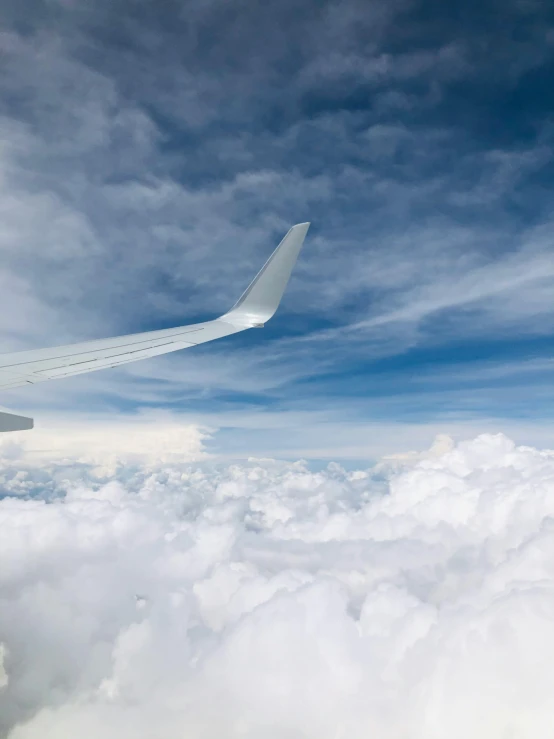 the wing of an airplane flying above the clouds, pexels contest winner, surrealism, thumbnail, layered stratocumulus clouds, over-shoulder shot, view from the side”