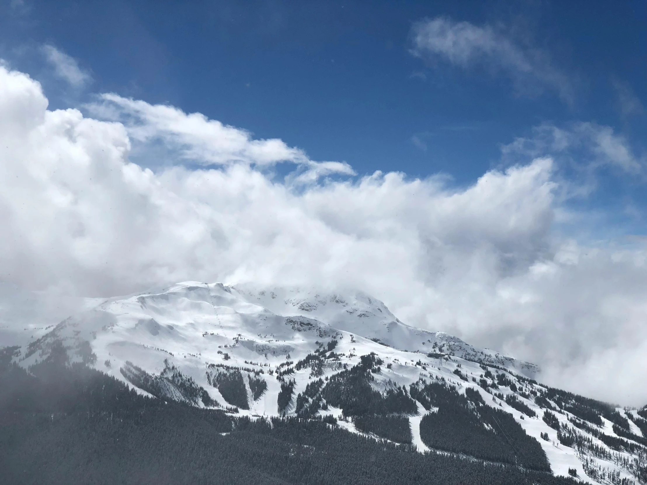 a man riding skis down a snow covered slope, by Carey Morris, pexels contest winner, puffy white clouds, whistler, seen from a distance, photograph of april