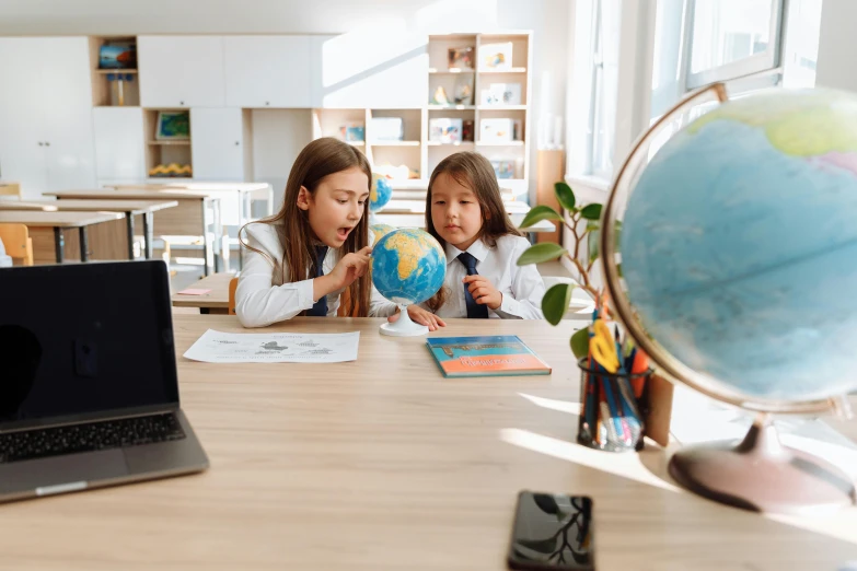 a couple of kids sitting at a table with a laptop, pexels contest winner, danube school, earth globe on top, avatar image, two girls, standing in class