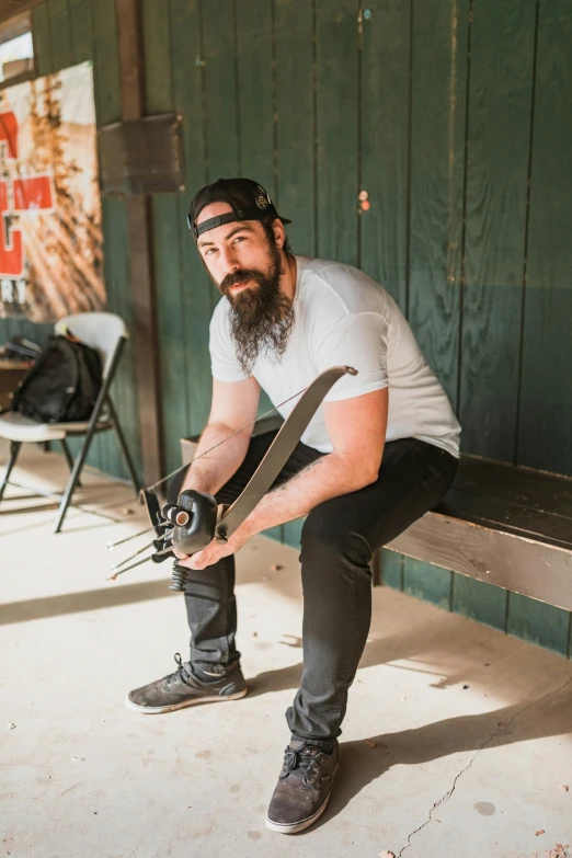 a man sitting on a bench holding a pair of skis, by Drew Tucker, auto-destructive art, with a beard and a black shirt, promo image, profile image, show