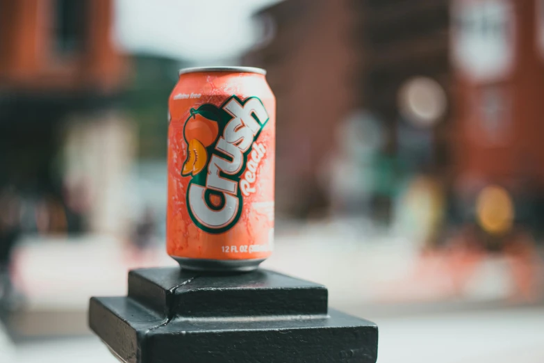 a can of orange soda sitting on top of a black post, by Carey Morris, pexels contest winner, crisp face, uwu hi-fructose, reds), caps sideways