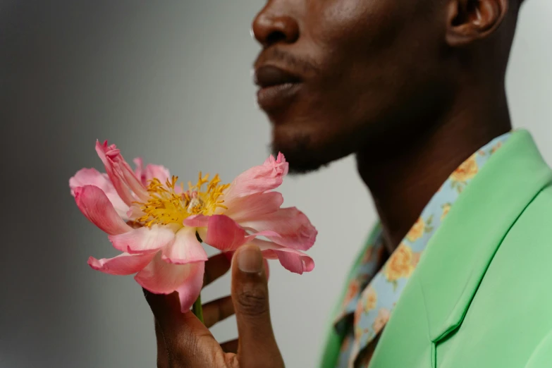 a close up of a person holding a flower, an album cover, inspired by Barthélemy Menn, trending on pexels, man is with black skin, pink white and green, taken with sony alpha 9, elegantly dressed