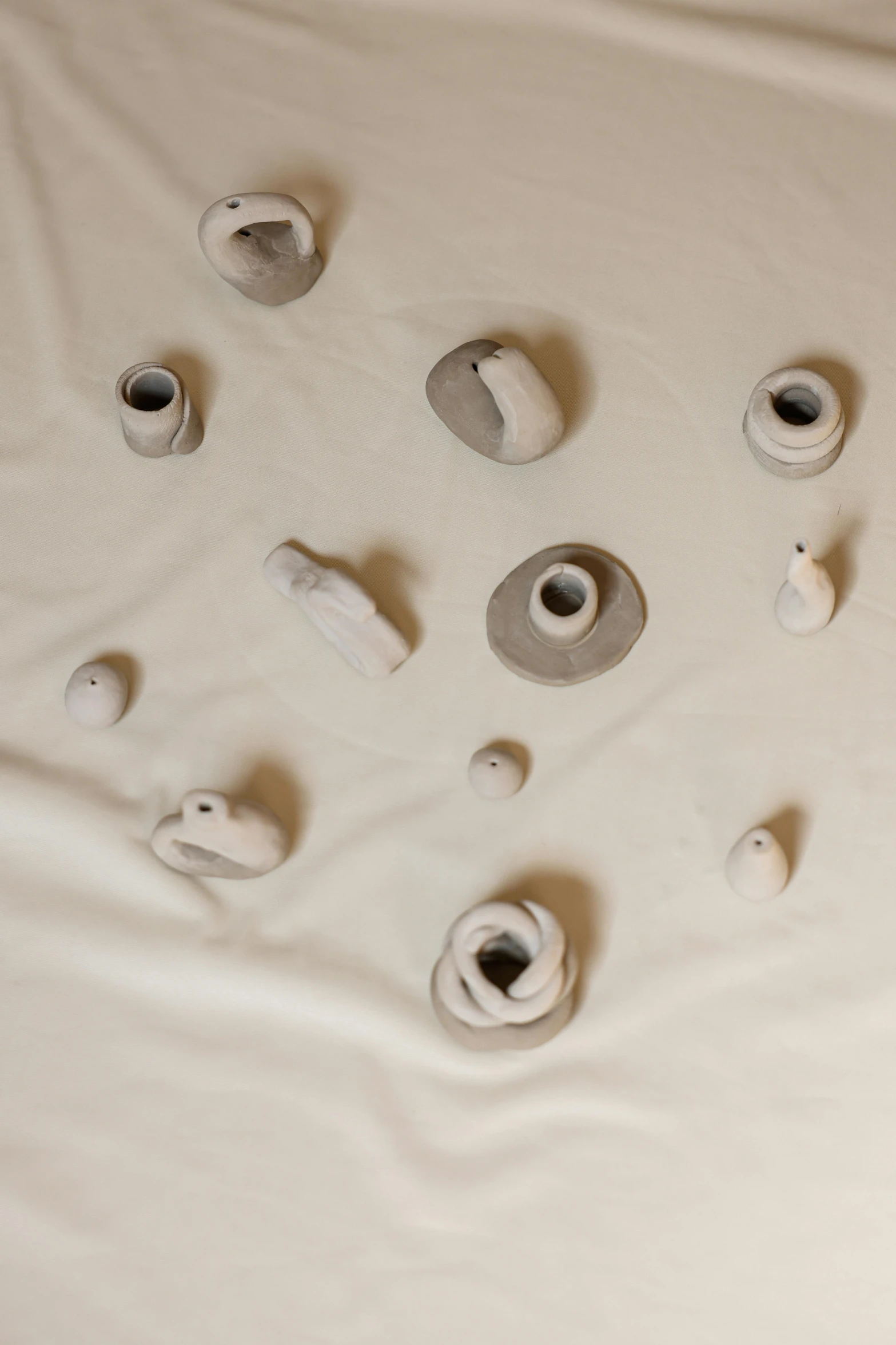 a pile of toilet paper sitting on top of a bed, inspired by Lucio Fontana, clay amulets, porcelain organic, taejune kim, grey