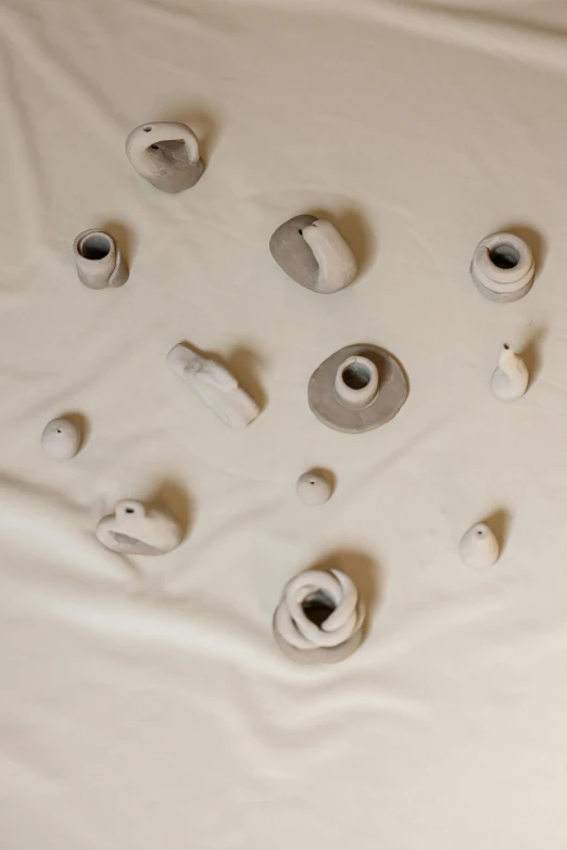 a pile of toilet paper sitting on top of a bed, inspired by Lucio Fontana, clay amulets, porcelain organic, taejune kim, grey