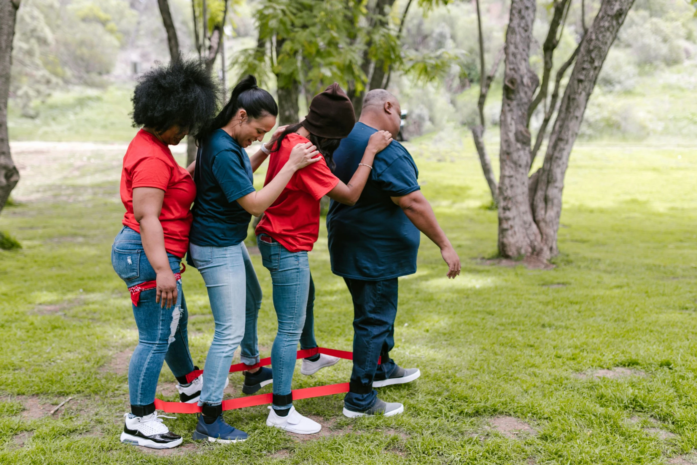 a group of young people standing next to each other, by Julia Pishtar, pexels contest winner, figuration libre, playing games, red ribbon, of a family standing in a park, with his back turned