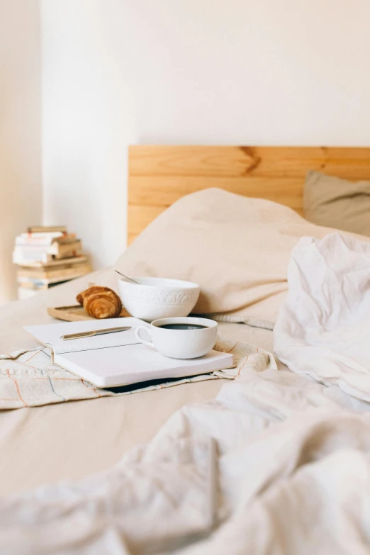 a bed with a tray of food on top of it, trending on unsplash, minimalism, beige, morning coffee, curled up under the covers, manuka