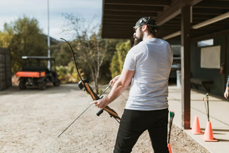 a man that is standing in the dirt with a bow, profile image, full product shot, outside, brown