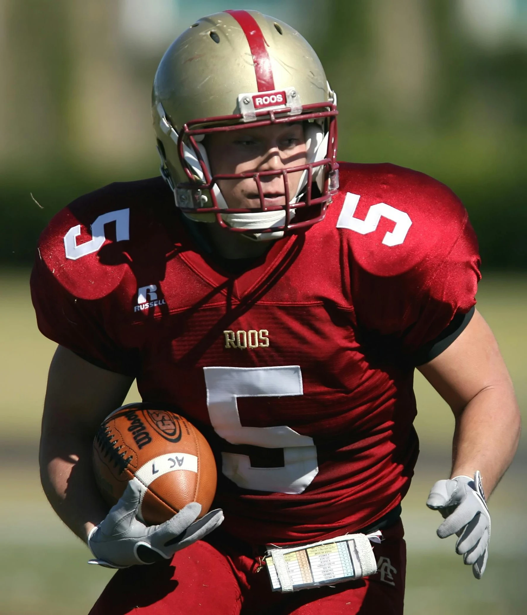 a man running with a football on a field, by Carey Morris, reddit, renaissance, maroon and white, full face shot, blond, taken in the late 2010s