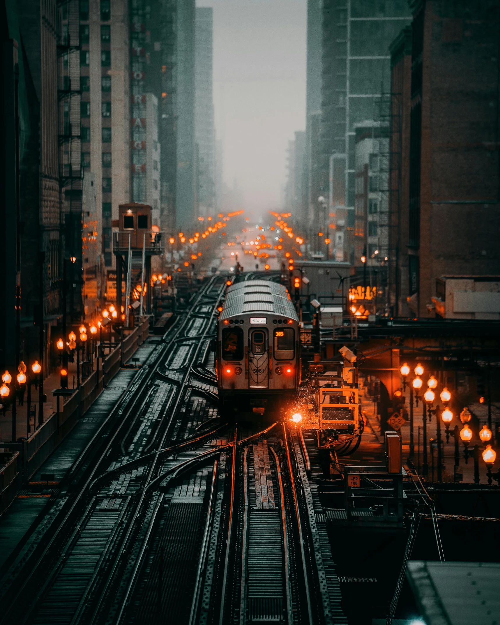 a train traveling down train tracks next to tall buildings, unsplash contest winner, orange lights, modern chicago streets, gif, 2 0 2 2 photo