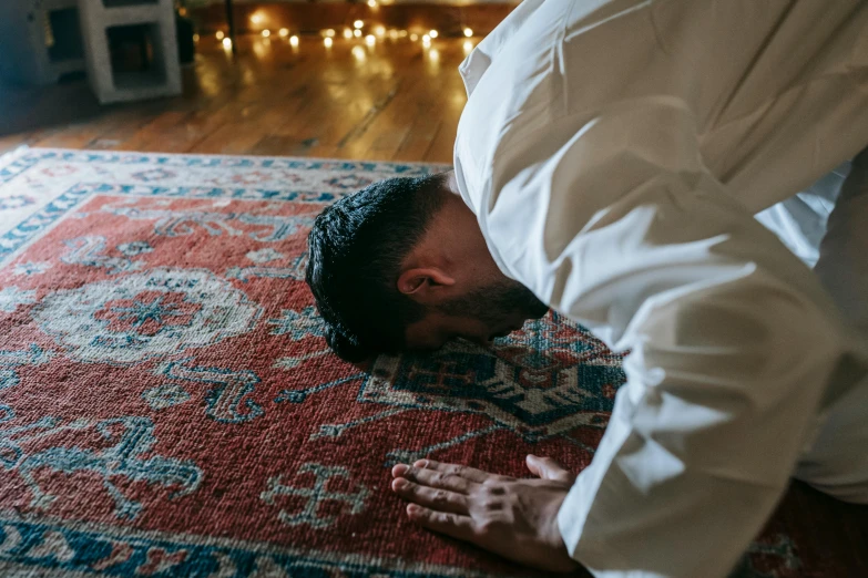 a man is doing a handstand on a rug, by Julia Pishtar, hurufiyya, kneeling in prayer, asleep, indoor setting, muslim