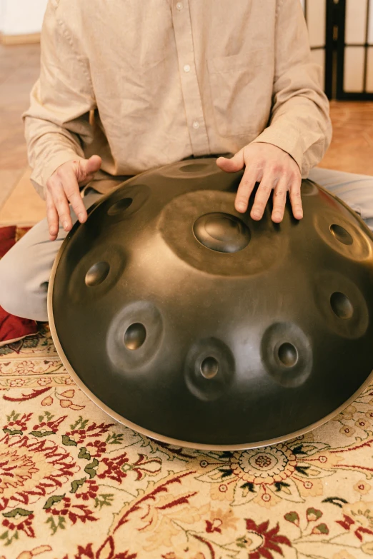 a man sitting on the floor holding a steel pan, inspired by Gong Xian, healing pods, black round hole, soft vinyl, full-size