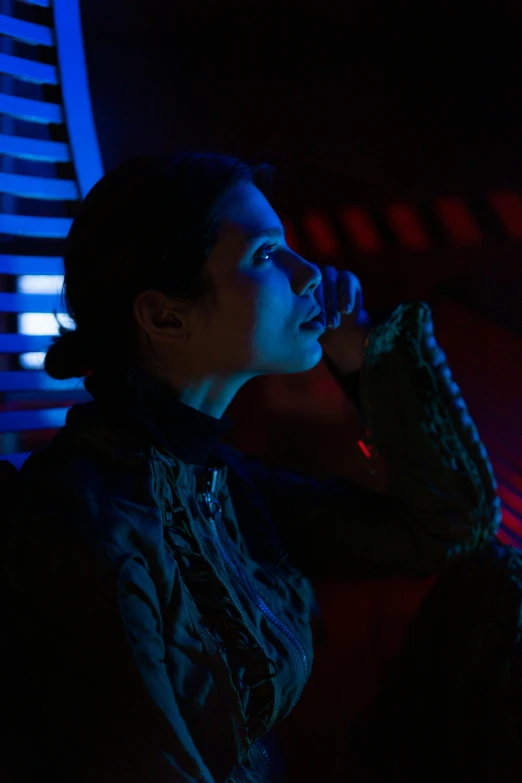 a woman talking on a cell phone in a dark room, star wars vibe, blue and red lighting, slide show, pensive