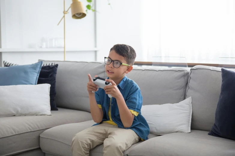 a young boy sitting on a couch playing a video game, pexels contest winner, square rimmed glasses, blippi, medium portrait, high definition screenshot