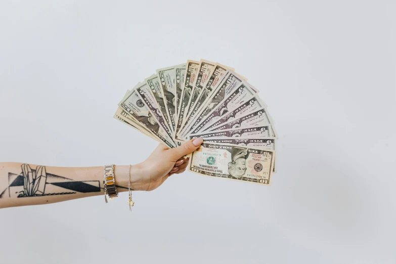 a person holding a fan of money in their hand, by Matija Jama, pexels contest winner, with a white background, background image, half asian, stacked