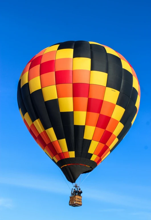 a colorful hot air balloon flying through a blue sky, by Dave Melvin, happening, black and yellow and red scheme, thumbnail, high-angle, exterior shot