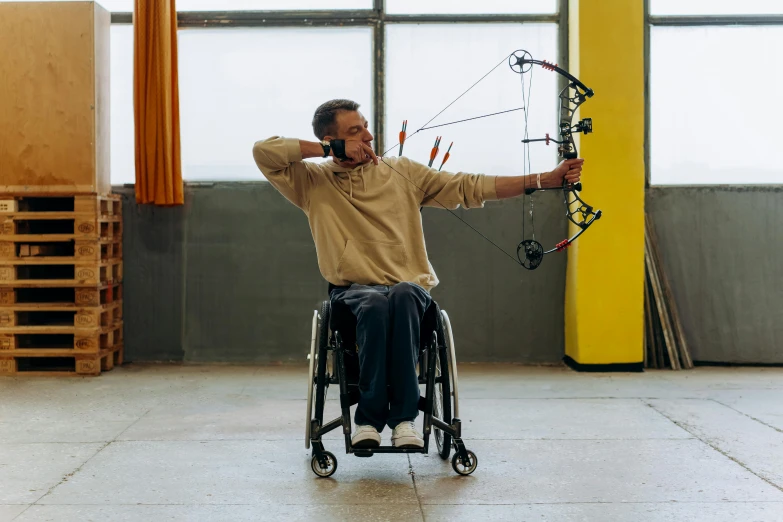 a man in a wheelchair holding a bow and arrow, pexels contest winner, repetitiveness, épaule devant pose, middle shot, center punched