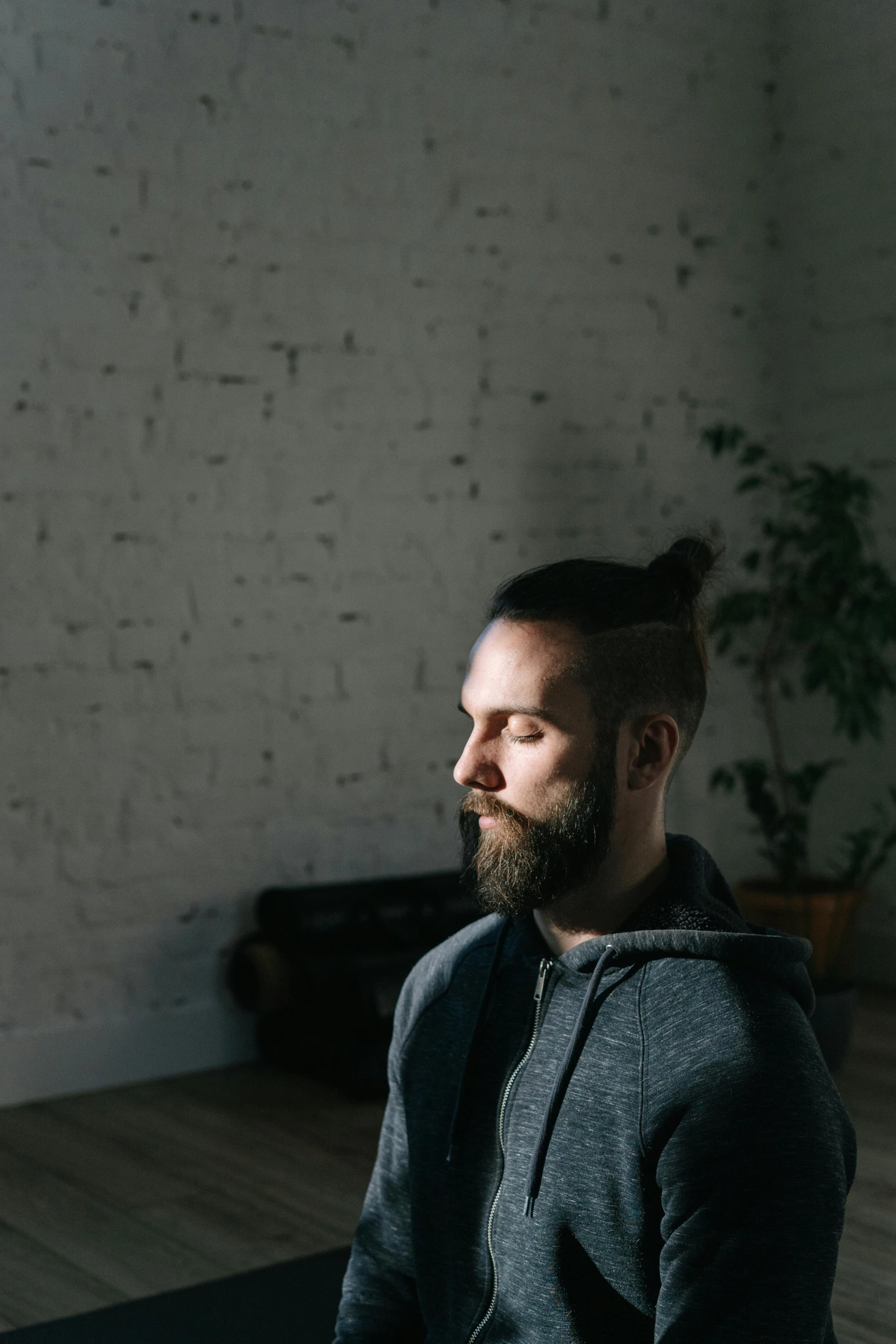 a man with a beard sitting on a yoga mat, by Adam Marczyński, trending on unsplash, light and space, profile image, looking from shoulder, in a room, low quality photo