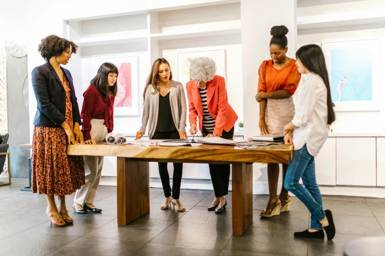 a group of women standing around a wooden table, pexels contest winner, wearing a designer top, people at work, award-winning art, people shopping