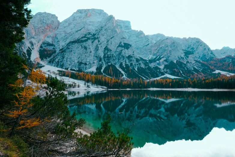 a lake with a mountain in the background, pexels contest winner, teal and orange colours, dolomites, mirrored, grey