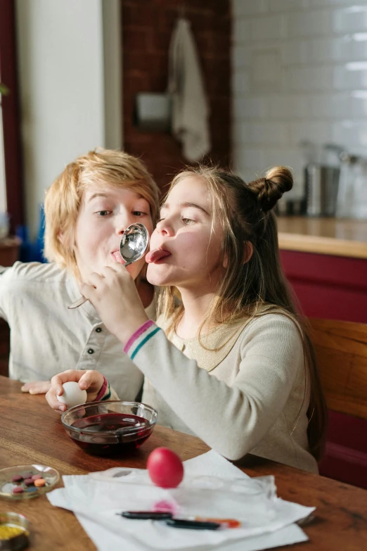 a couple of women that are sitting at a table, by Adam Marczyński, pexels contest winner, eggs, licking out, young teen, spoon placed