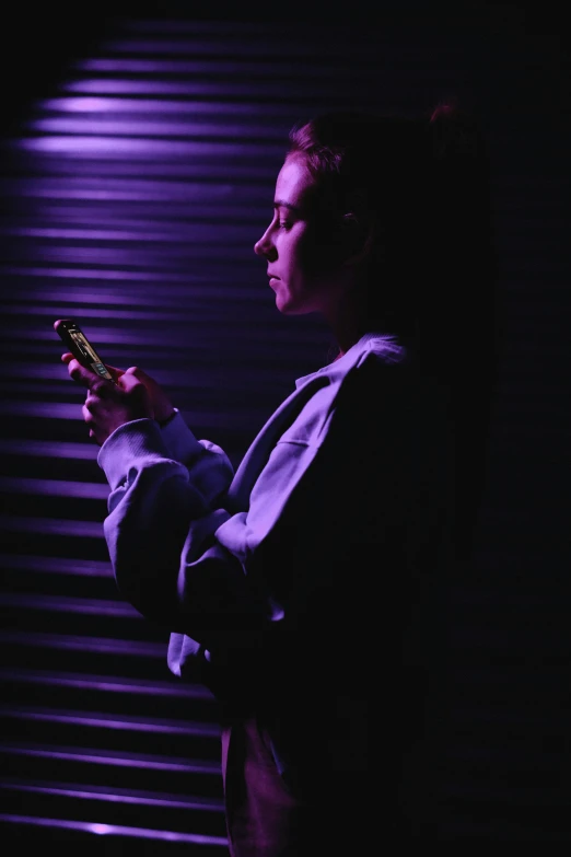 a man looking at his cell phone in the dark, a portrait, pexels, ((purple)), photograph of a techwear woman, film noir lighting, purple and yellow lighting